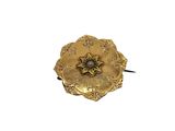 a gold flower brooch with a diamond in the center