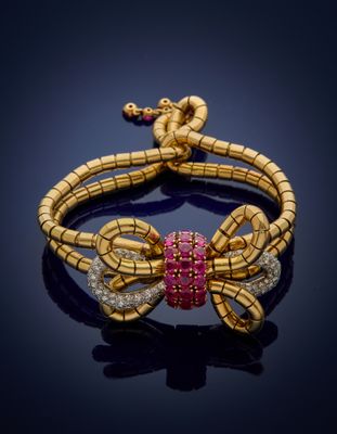 a gold snake bracelet with pink and white diamonds
