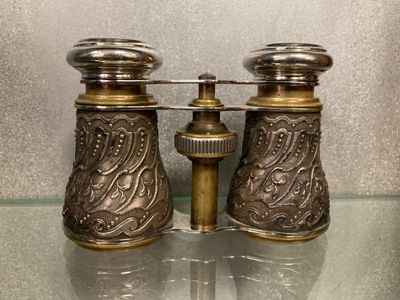 une paire de salières et poivrières anciennes en laiton posées sur une table en verre