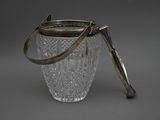 a glass jar with a metal handle on a gray surface