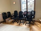four black office chairs in a room with a large window