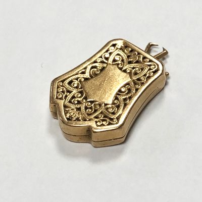 a gold pendant with a picture on it on a white surface