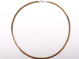 gros plan d'un collier en or sur fond blanc