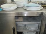 several plates are stacked on top of a metal counter in a kitchen