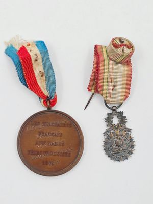 Deux médailles sont posées sur une surface blanche : l'une est une médaille et l'autre est une médaille.