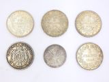 six different british coins are arranged in a row on a white surface
