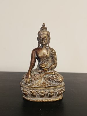 statue of a buddha sitting on a lotus position on a black table