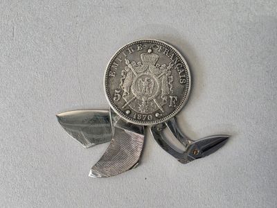 a silver coin and a knife on a white surface