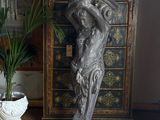 a statue of a woman holding a vase on top of a dresser