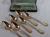 six silver spoons in a case on a white table cloth