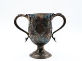 une tasse en argent posée sur une surface blanche