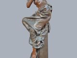 bronze statue of a woman sitting on a pedestal with her hand on her chin