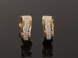 a pair of gold and diamond earrings on a black surface