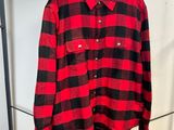 une chemise à carreaux rouges et noirs suspendue à un portant