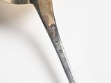 a silver spoon with a spoon handle on a white surface