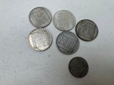 six types différents de pièces d'argent sur une surface blanche