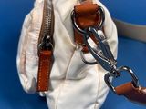 a white purse with a brown strap on a blue background