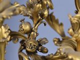 a gold clock that is hanging from a gold chandelier