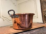 a large copper pot sitting on top of a wooden table