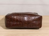 a brown leather toilet bag sitting on top of a wooden table