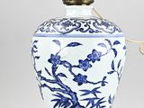 a blue and white vase on a table with a lamp on it