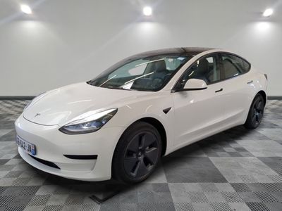 La Tesla Model 3 blanche est garée dans une pièce dont le sol est à carreaux.