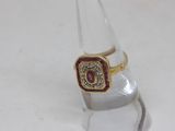 a gold ring with a red stone on top of a clear glass