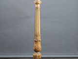 a tall gold candle holder on a concrete floor