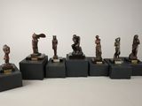 six bronze figurines of different sizes and shapes on black bases