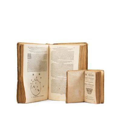 an open book sitting on top of a white surface next to a stack of books
