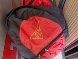 a red and black backpack with a yellow triangle on it
