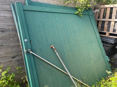 une porte verte appuyée contre une clôture en bois