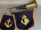 two navy pennants hanging on a wall next to a trumpet