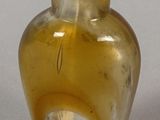 a small glass bottle with a green lid on a table