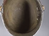 a silver vase with a handle on a white table