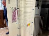 un homme debout à côté d'un portemanteau métallique sur lequel sont suspendus des vêtements