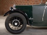 a green car parked in front of a brick wall