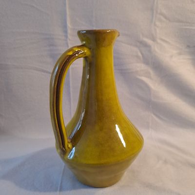 un vase jaune posé sur une surface blanche