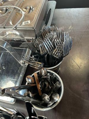 de nombreuses cuillères et fourchettes dans un saladier posé sur une table