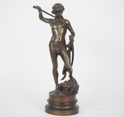 une statue en bronze représentant un homme tenant une épée, posée sur un socle en bois