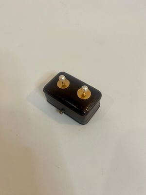 une petite boîte noire ornée de deux clous dorés