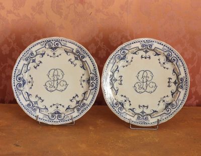 deux assiettes bleues et blanches ornées d'un monogramme, posées sur une table
