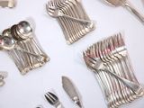 a lot of silverware on a table with a white table cloth