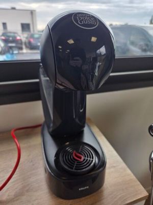 une cafetière noire posée sur une table près d'une fenêtre