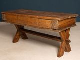 an old wooden table with a wooden top on a white floor