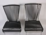 pair of black metal chairs with slats on them against a white wall