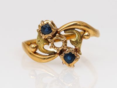 une image représentant une bague en or sertie de pierres bleues sur un fond blanc