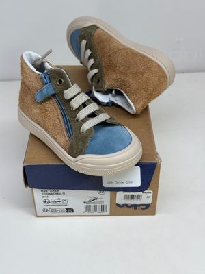 une paire de chaussures pour enfants dans une boîte posée sur une surface blanche
