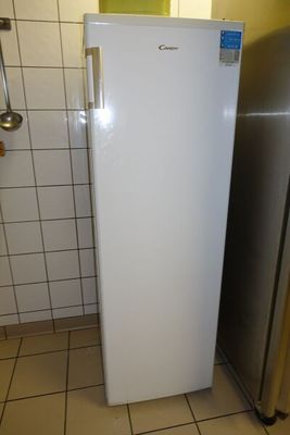 un réfrigérateur blanc dans un coin d'une pièce carrelée