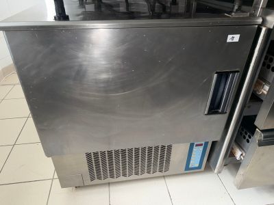 a stainless steel refrigerator in the middle of a tiled floor